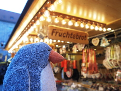 Pinguin will Früchtebrot auf dem Weihnachtsmarkt essen